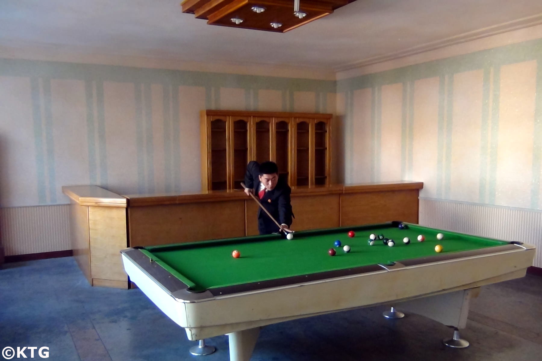 North Korean man playing pool at the Jangsusan Hotel in Pyongsong city, North Korea, DPRK