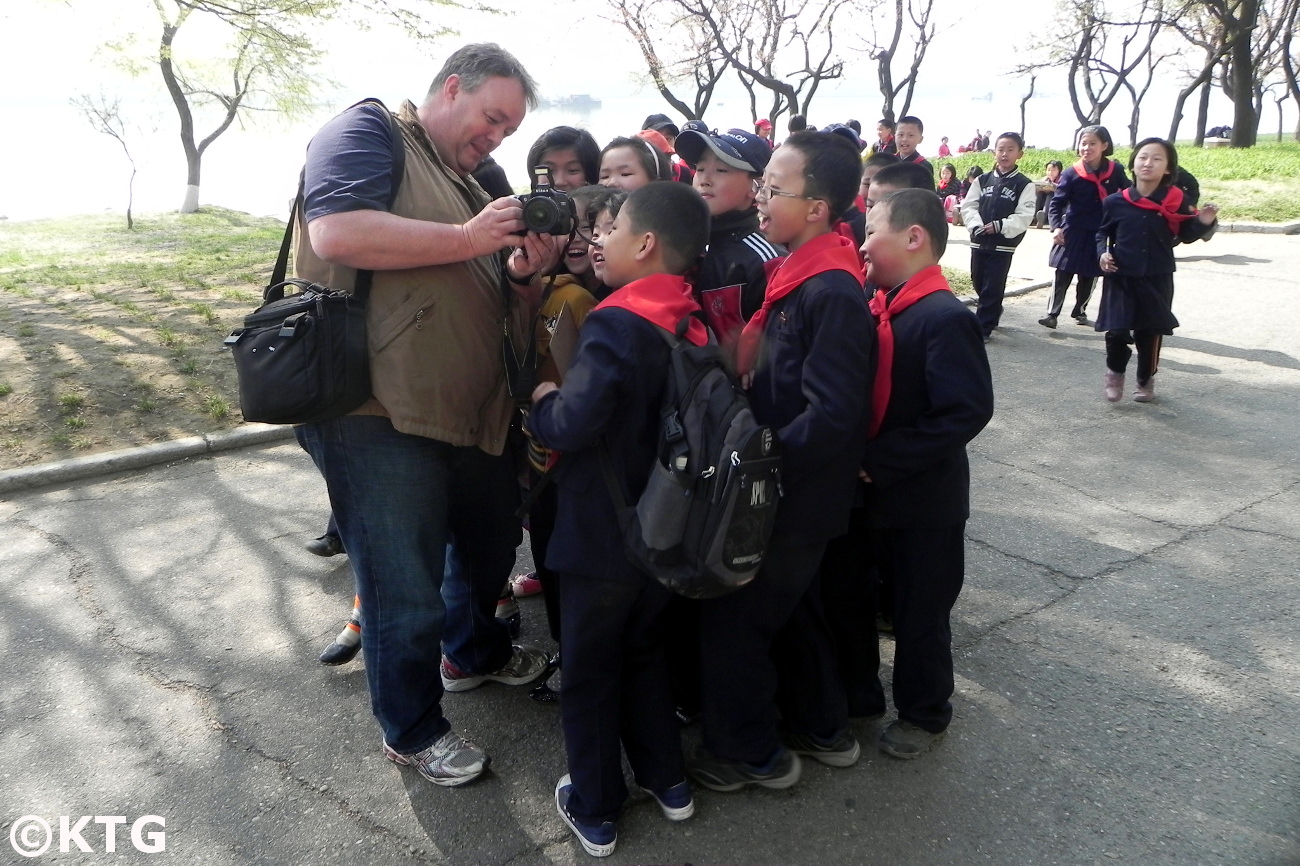 KTG-Reisender zeigt nordkoreanischen Kindern ein gerade aufgenommenes Bild. Dies war am Taedong-Fluss in Pjöngjang, der Hauptstadt der DVRK (Nordkorea). Reise arrangiert von KTG Tours