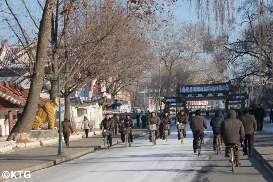 North Koreans cycling in winter in Sariwon city. This is the capital of North Hwanghae province in North Korea ie DPRK. Trip arranged by KTG tours