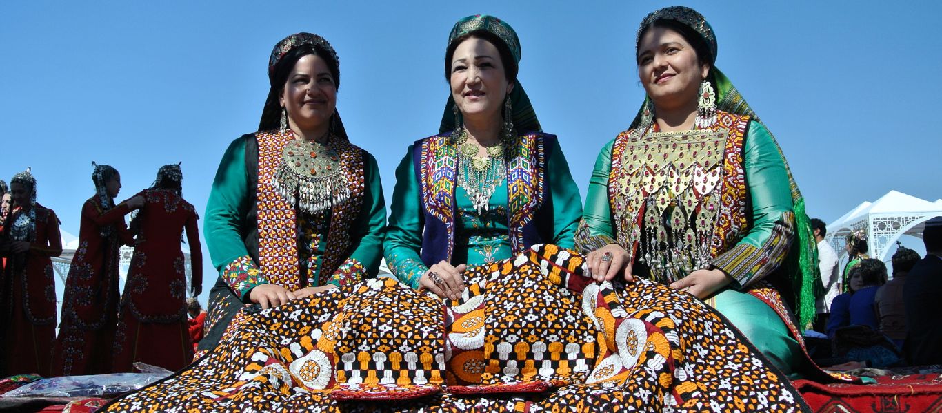 Turkmen ladies in traditional clothes making a carpet, Turkmenistan