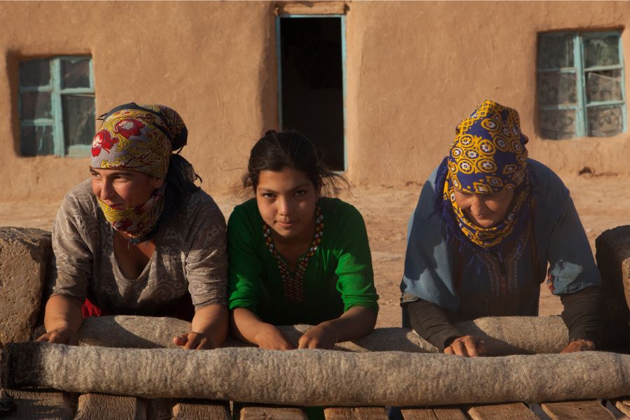 Women and a girl making carpets in Turkmenistan