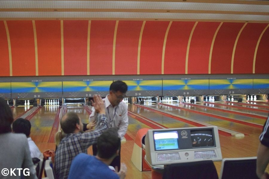 KTG traveller high fiving with a North Korean guide at the Pyongyang Gold Lane Bowling alley in Pyongyang, North Korea